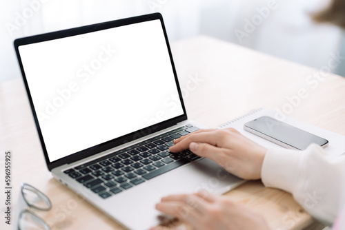 Lady using laptop with white screen on wooden table.
