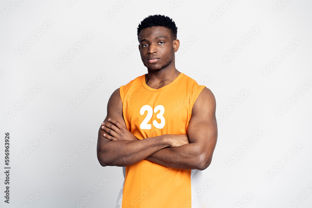 Portrait of handsome muscular African man, serious basketball player with arms crossed looking at camera, isolated on white background. Sport concept Portrait of handsome muscular African man, serious basketball player with arms crossed looking at camera, isolated on white background. Sport concept