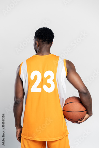 Back view of basketball player wearing basketball uniform, holding ball isolated on white background. Sport concept