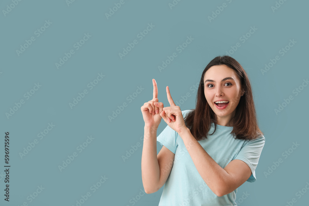 Young woman pointing at something on blue background Young woman pointing at something on blue background