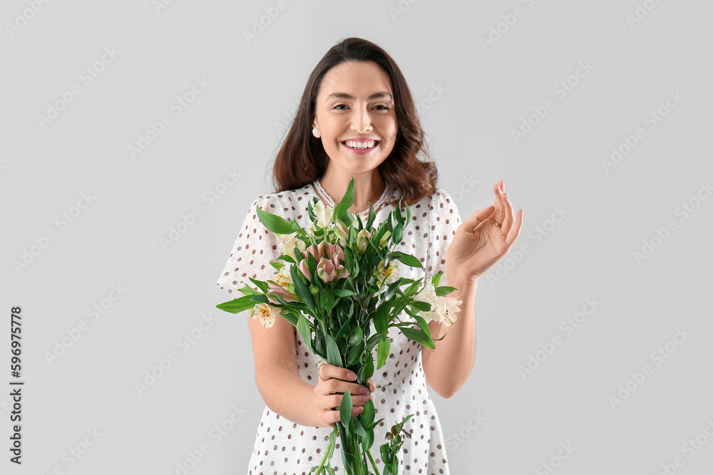 Young woman in dress with alstroemeria flowers on grey background Young woman in dress with alstroemeria flowers on grey background