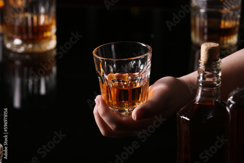 Woman holding glass of cold rum at table