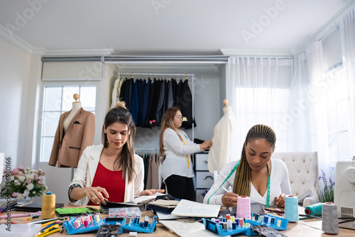 Diverse women fashion designer work design clothes in tailoring atelier. 