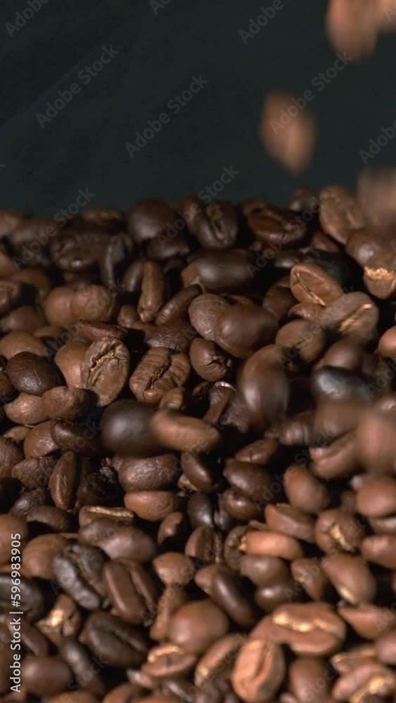 Vertical slow motion of roasted coffee beans falling. Organic coffee seeds. Vertical slow motion of roasted coffee beans falling. Organic coffee seeds.