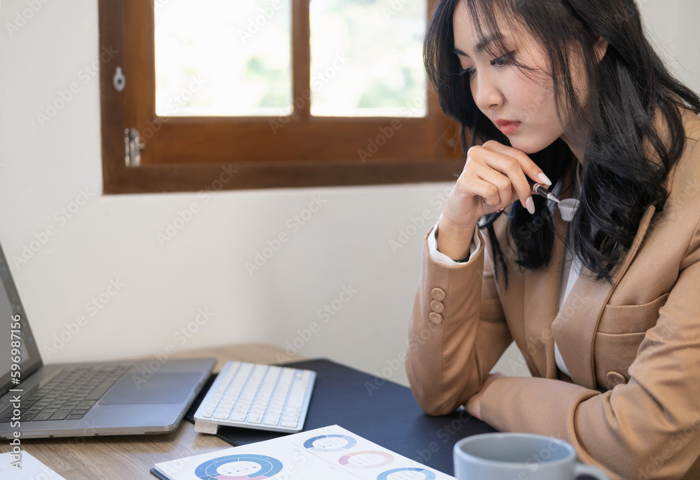 Business woman pondering over ideas for new business project.Young thoughtful Asian business woman executive manager wearing suit working in modern office, analyzing document .