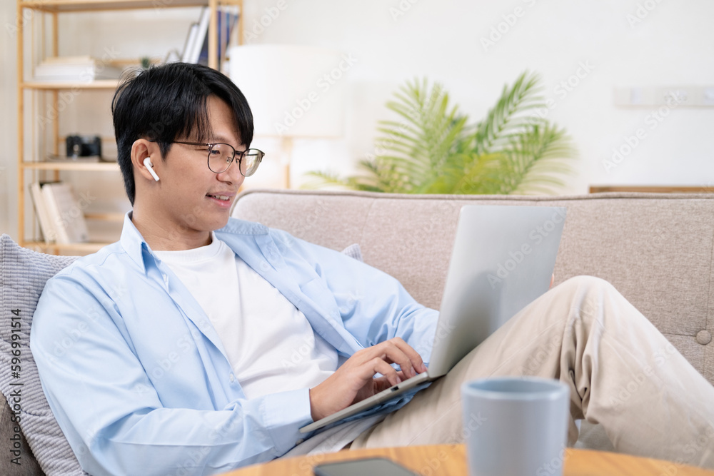 Pleasant happy man communicating in social network, searching information online.Young male using laptop and smiling at home. Man sitting by table working on laptop computer. Pleasant happy man communicating in social network, searching information online.Young male using laptop and smiling at home. Man sitting by table working on laptop computer.