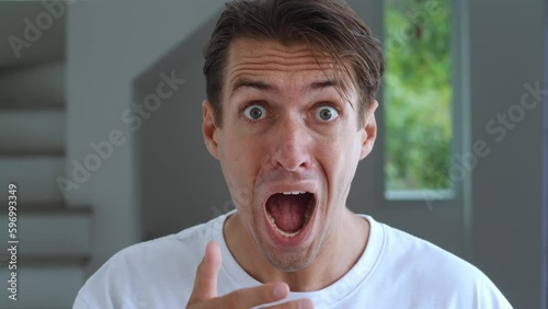 Scared male 30s screams in panic, seeing something terrible. Portrait of really scared millennial man afraid of horror, standing at home background. Horror and human fear concept.