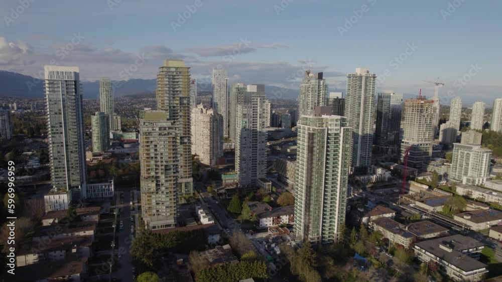 Aerial pan around tall skyscrapers with mountains in the background near Vancouver, BC Aerial pan around tall skyscrapers with mountains in the background near Vancouver, BC