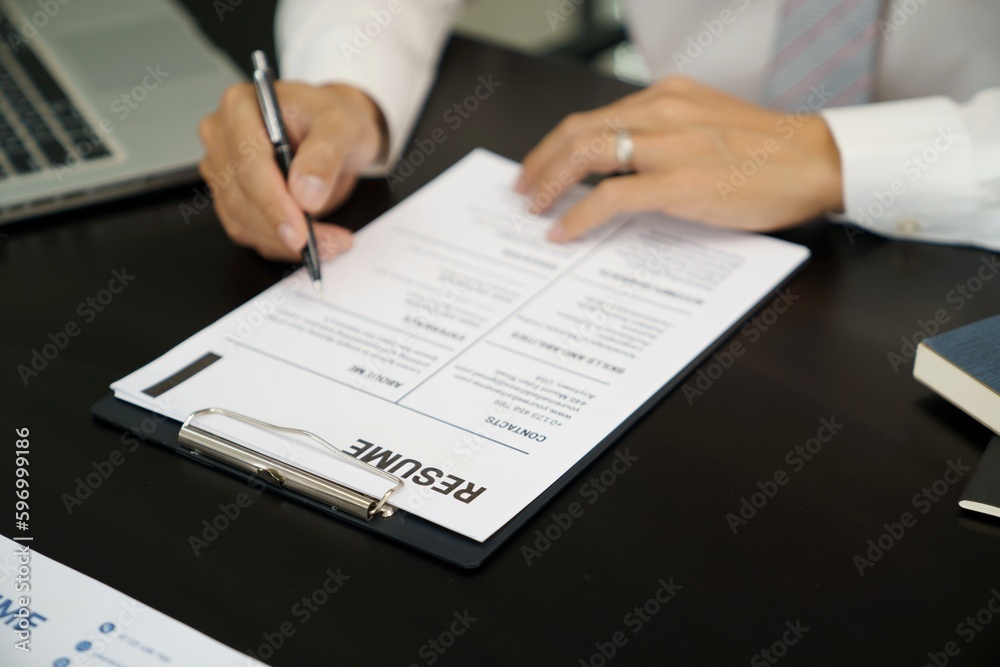 Examiner reading a resume during job interview at office Business and human resources concept. Examiner reading a resume during job interview at office Business and human resources concept.