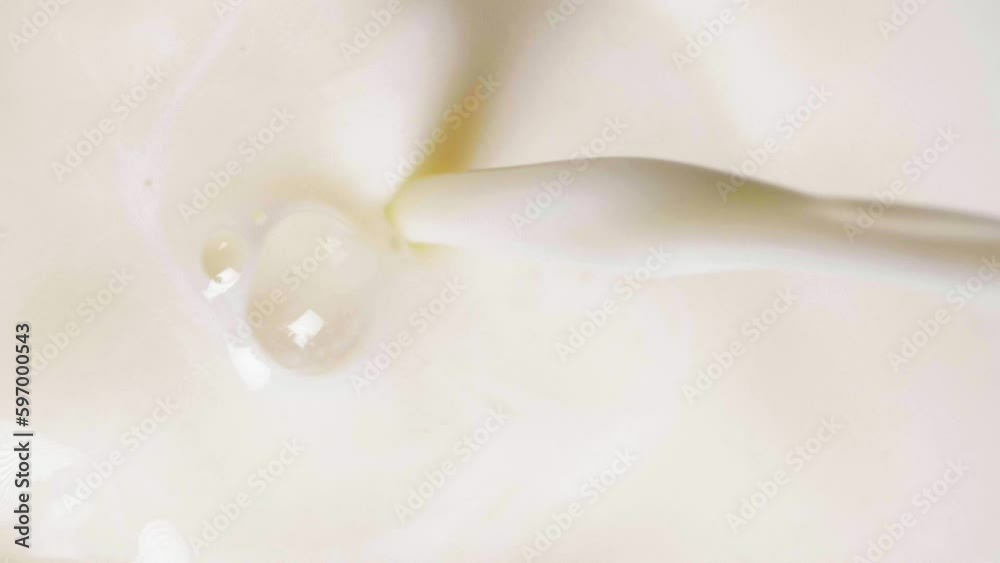 Close-up vertical shot of vegan oat milk pouring into a glass in slow motion