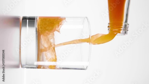 Slow motion shot of carrot juice being poured into a glass against a white background photo