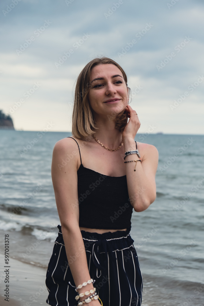 Young woman standing on blurred beachside background. Attractive female enjoying walking the sea shore. travel and active lifestyle concept. Springtime. Relaxation, youth, love, lifestyle solitude Young woman standing on blurred beachside background. Attractive female enjoying walking the sea shore. travel and active lifestyle concept. Springtime. Relaxation, youth, love, lifestyle solitude