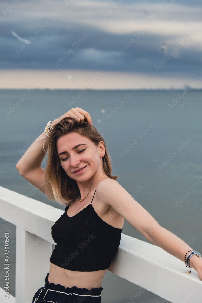 Young woman standing on wooden pier blurred beachside background. Attractive female enjoying the sea shore travel and active lifestyle concept. Springtime. Wellness wellbeing mental health inner peace Young woman standing on wooden pier blurred beachside background. Attractive female enjoying the sea shore travel and active lifestyle concept. Springtime. Wellness wellbeing mental health inner peace