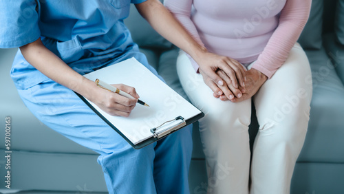 Asian Chinese female physiotherapist caregiver helping elderly woman exercise for recovery, prevention of osteoarthritis and osteoporosis.