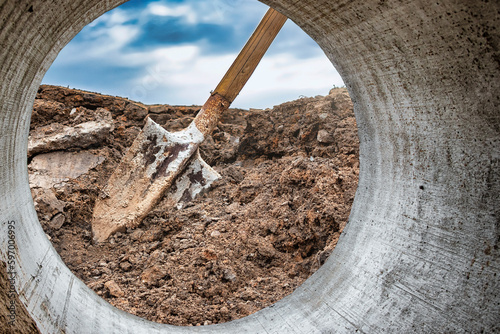 Dirty shovel in fresh soil at a construction site in a pit. Deep hole in the ground. Earthworks, manual refinement of the soil. Dig deep ditches and holes. photo