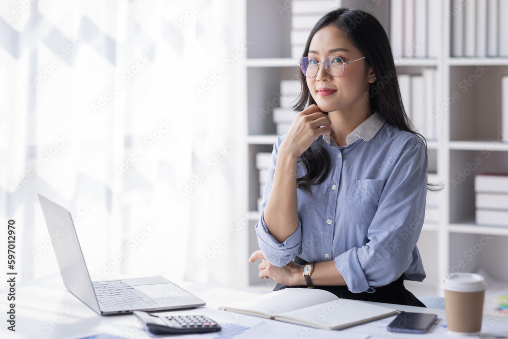 Asian Business woman using calculator and laptop for doing math finance on an office desk, tax, report, accounting, statistics, and analytical research concept
