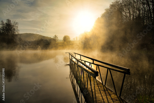 Sunrise with dust over lake with a bridge