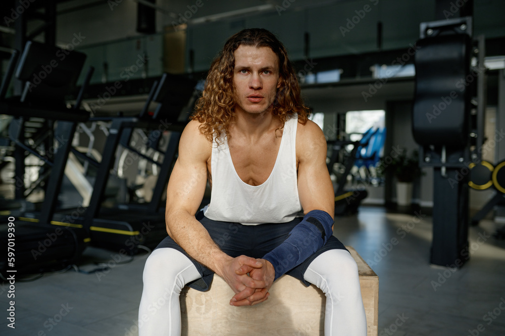 Portrait of tired sportsman sitting on fitness box while rest after training Portrait of tired sportsman sitting on fitness box while rest after training