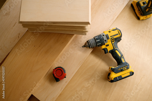Electric drill, ruler and wooden board at carpenter workplace