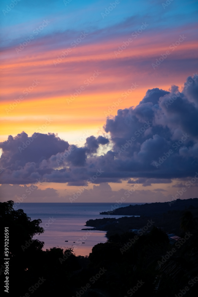 Colorful sunset with orange to blue sky and blue clouds above the Caribbean Sea in Saint Pierre on Martinique tropical island. French overseas department is a popular tourist and cruise destination.