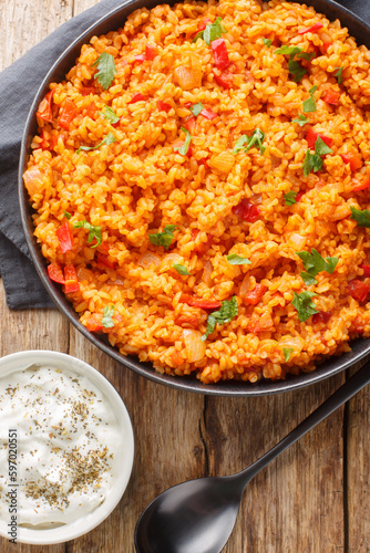 Turkish style bulgur pilaf is a classic hearty and healthy side dish close-up in a bowl on a wooden table. Vertical top view from above