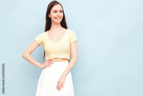 Image portrait of optimistic woman in yellow t-shirt and white skirt. Carefree stylish model with long hair. Smiling female posing in studio. Isolated. Looks delightful and cute. Slim