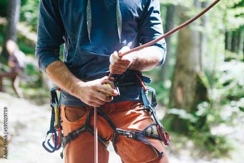 Close up shot of a man's hands holding a rock climbing belaying device