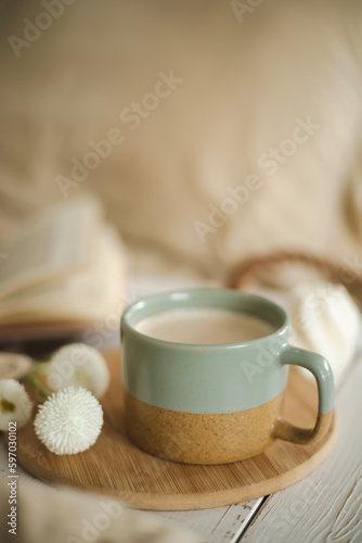 A cup of warm, warming aromatic tea, coffee, flowers nearby