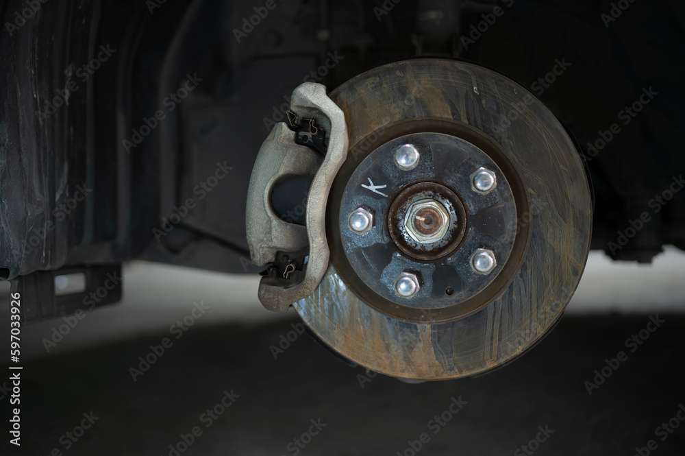 A auto mechanic checking the condition of a car's brake discs that have been used for a while A auto mechanic checking the condition of a car's brake discs that have been used for a while