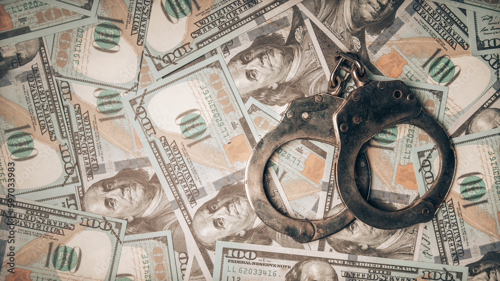 Handcuffs of a police officer lying on piles of dollar bills, bribery police, corrupt police. Handcuffs of a police officer lying on piles of dollar bills, bribery police, corrupt police.
