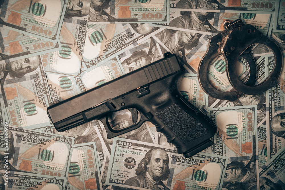 Police officer's handgun and handcuffs lying on stacks of dollar bills ...