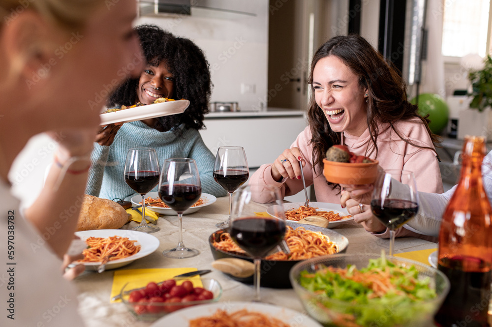 Details on the face of the woman laughing during a lunch of friends and relatives, meeting of young people of different ages and ethnicities, friends and family drink wine and eat italian food
