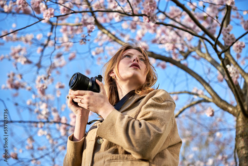 redhead girl taking photos in front of cherry blossom photo