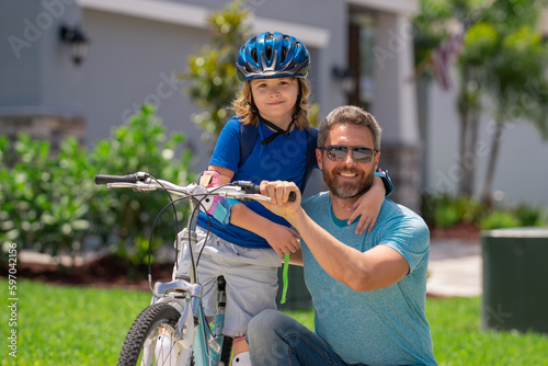 Fathers day. Father teaching son ride a bicycle. Father and son cycling on bike on summer day. Father playing with son outdoor. Father support child. Fathers love. Sporty kids.