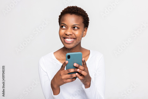 Charming african woman with short haircut holding cellphone in hands chatting messaging with someone boyfriend friends family holding new modern device in arms.