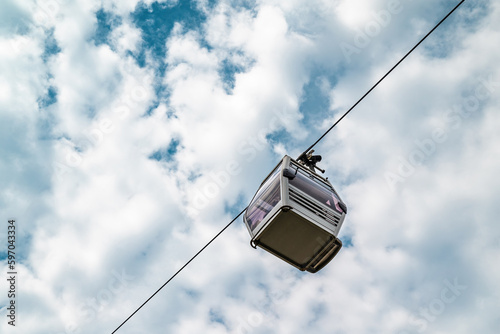 Bottom up view of cable car cabin in front of cloudy sky