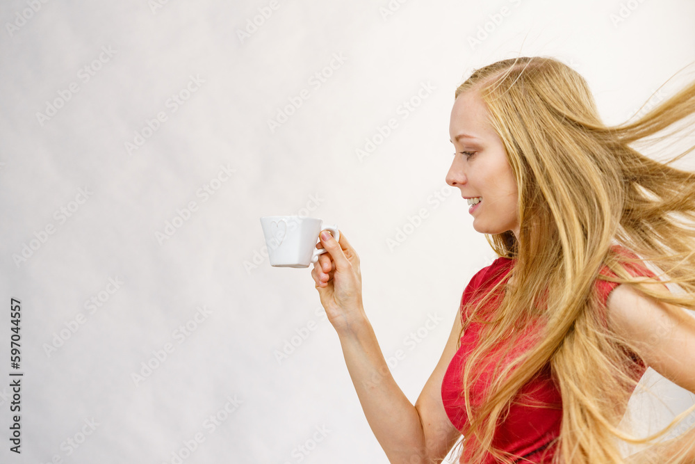 Blonde girl blowing hair holds coffee cup Blonde girl blowing hair holds coffee cup