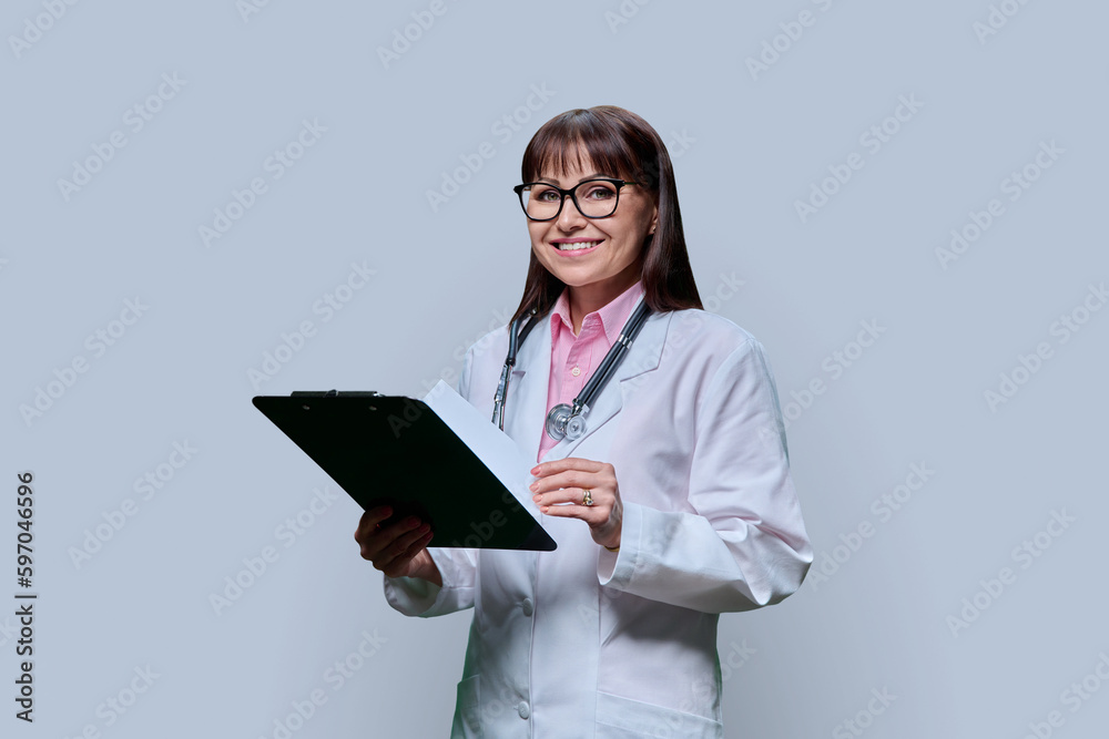 Female doctor with clipboard on gray studio background Female doctor with clipboard on gray studio background