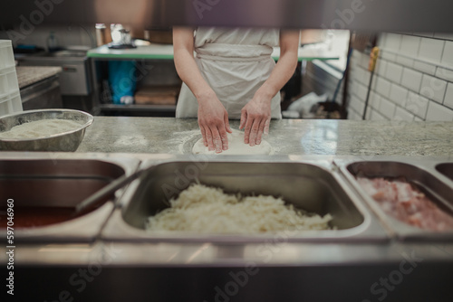 Hands of a cook kneading a pizza dough