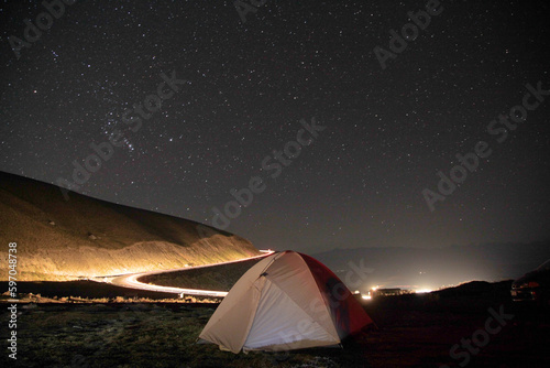 Timelapse. The tent stands above the starry sky among the mountains.