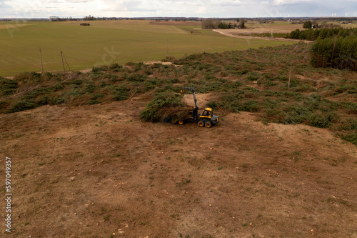 Drone photography of forestry machine piking up small trees and transporting