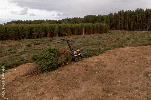 Drone photography of forestry machine piking up small trees and transporting