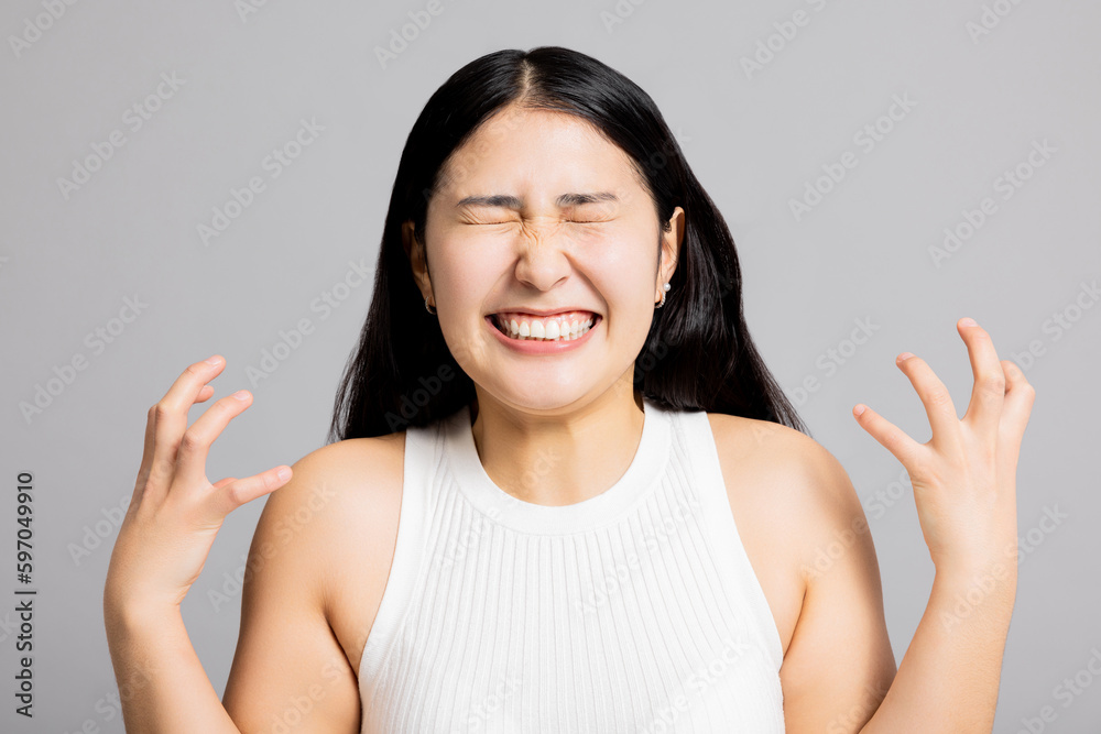 Delighted shocked asian young woman in basic clothes standing on grey background in studio isolated looking at camera smiling showing good mood deligtful exciting emotions. Delighted shocked asian young woman in basic clothes standing on grey background in studio isolated looking at camera smiling showing good mood deligtful exciting emotions.