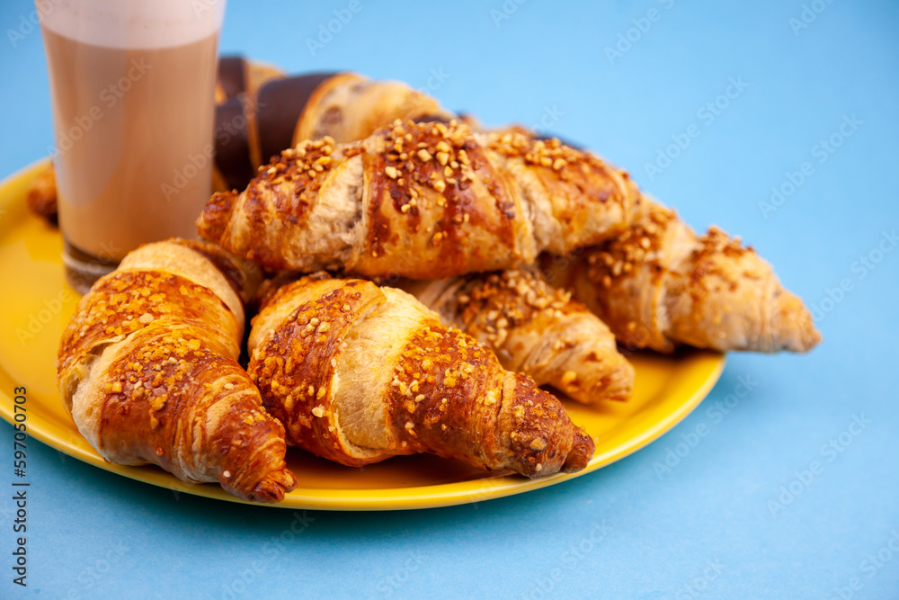 Chocolate croissants or croissant with nut crumbs on a plate. Delicious breakfast on the table. Tasty sweet baking dessert for coffee. Food background. Fresh buttery croissants rolls