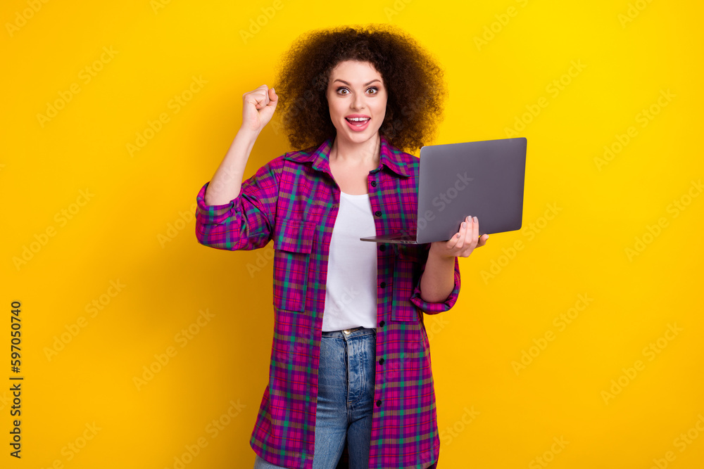 Photo of girl wear stylish checkered jacket raise fist up celebrating victory online gambling income hold netbook isolated on yellow color background Photo of girl wear stylish checkered jacket raise fist up celebrating victory online gambling income hold netbook isolated on yellow color background