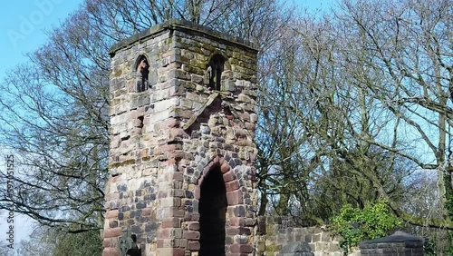 Historic Windleshaw Chantry stonework tower exterior slow motion around graveyard ruins against blue sky photo