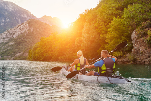 A group of friends enjoying fun and kayaking exploring the calm river, surrounding forest and large natural river canyons during an idyllic sunset. © .shock