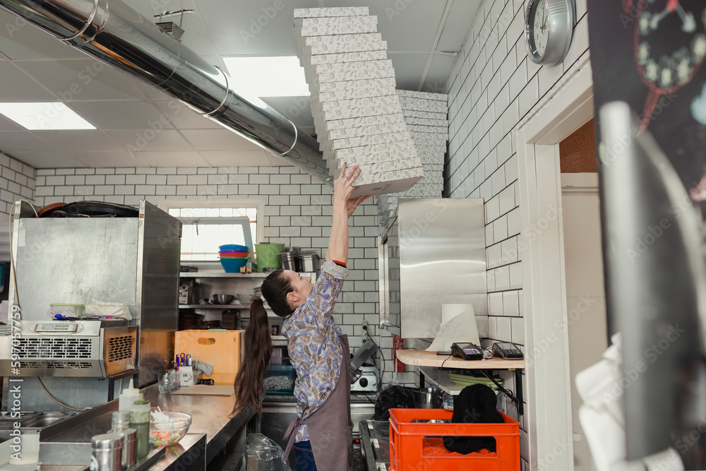 Female waitress preparing pizza boxes for orders