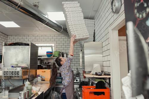 Female waitress preparing pizza boxes for orders