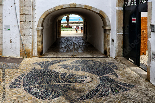 Lagos, Faro district, Algarve, Portugal, Europe, Calcada portuguesa - characteristic street paving in geometric patterns - here two fishes, Sao Goncalo gate in walls around historic part of town photo